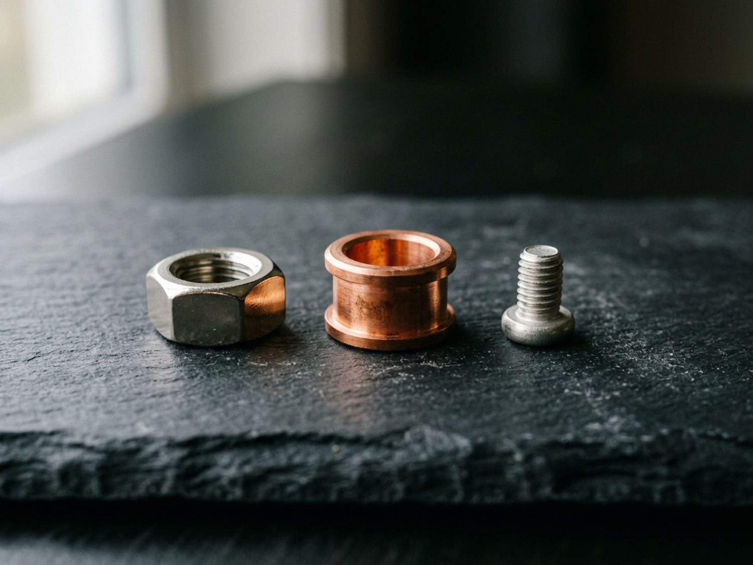 Three small metal parts in a row - nickel, copper and silver finishes
