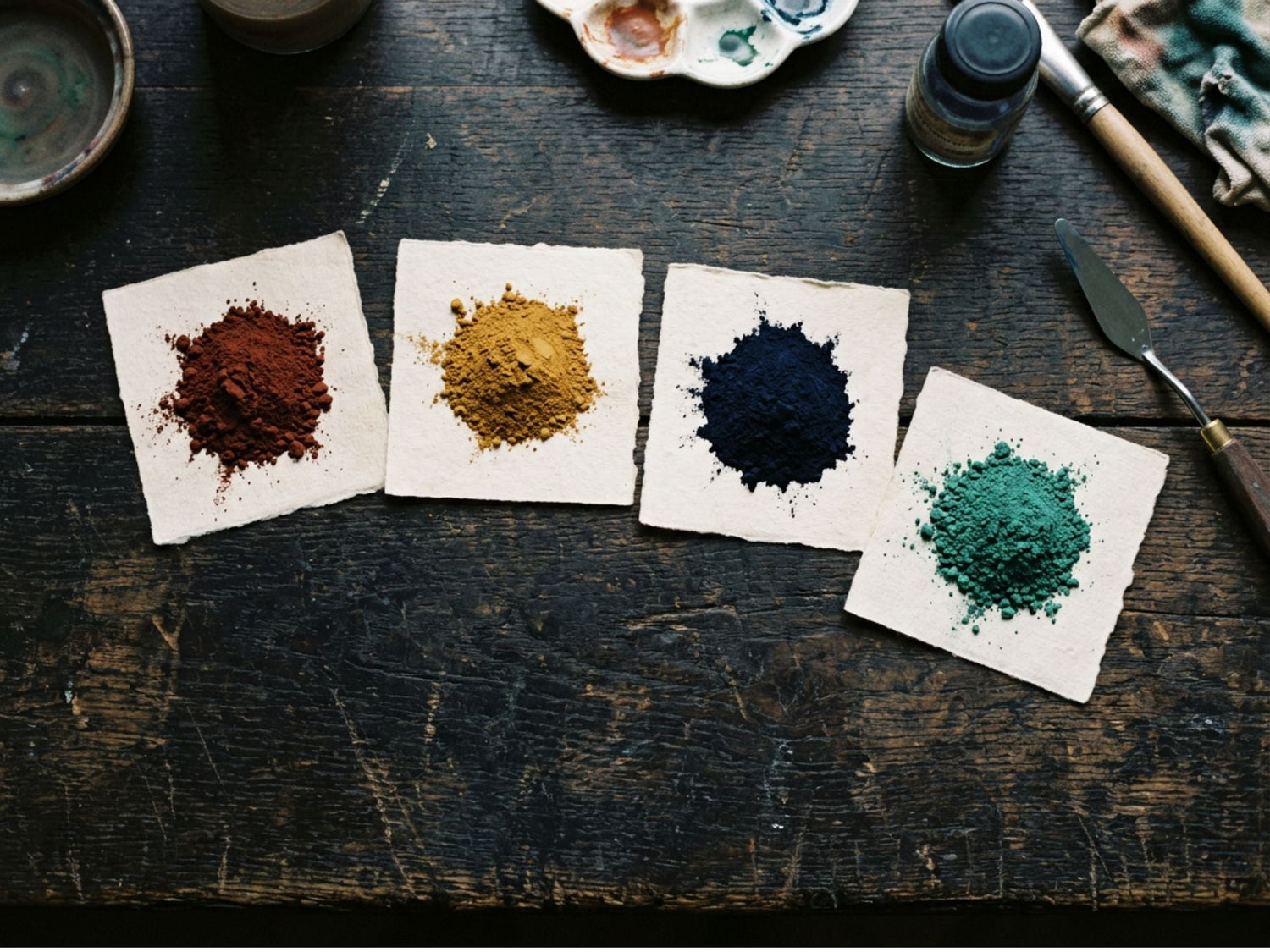 Four heaps of dry pigment powder - iron oxide red, ochre, ultramarine and charcoal